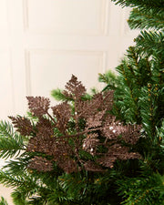 Set of three 19 cm mocha glitter leaf picks arranged among green Christmas tree branches.