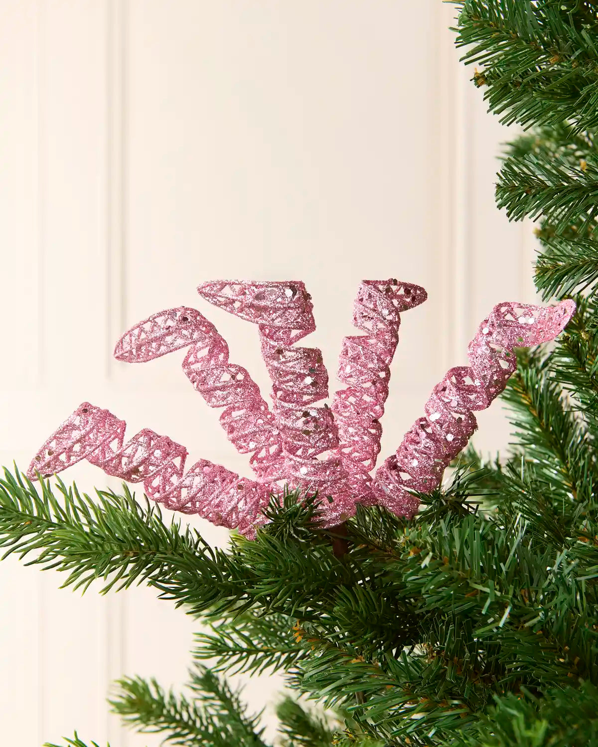 Set of three 18 cm pink glitter spiral picks arranged among green Christmas tree branches.
