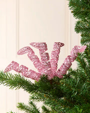 Set of three 18 cm pink glitter spiral picks arranged among green Christmas tree branches.