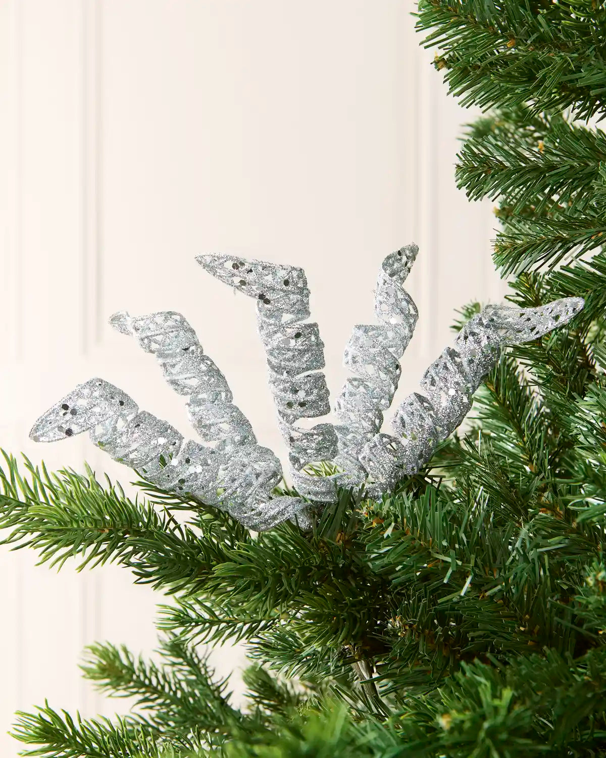 Set of three 18 cm silver glitter spiral picks arranged among green Christmas tree branches.