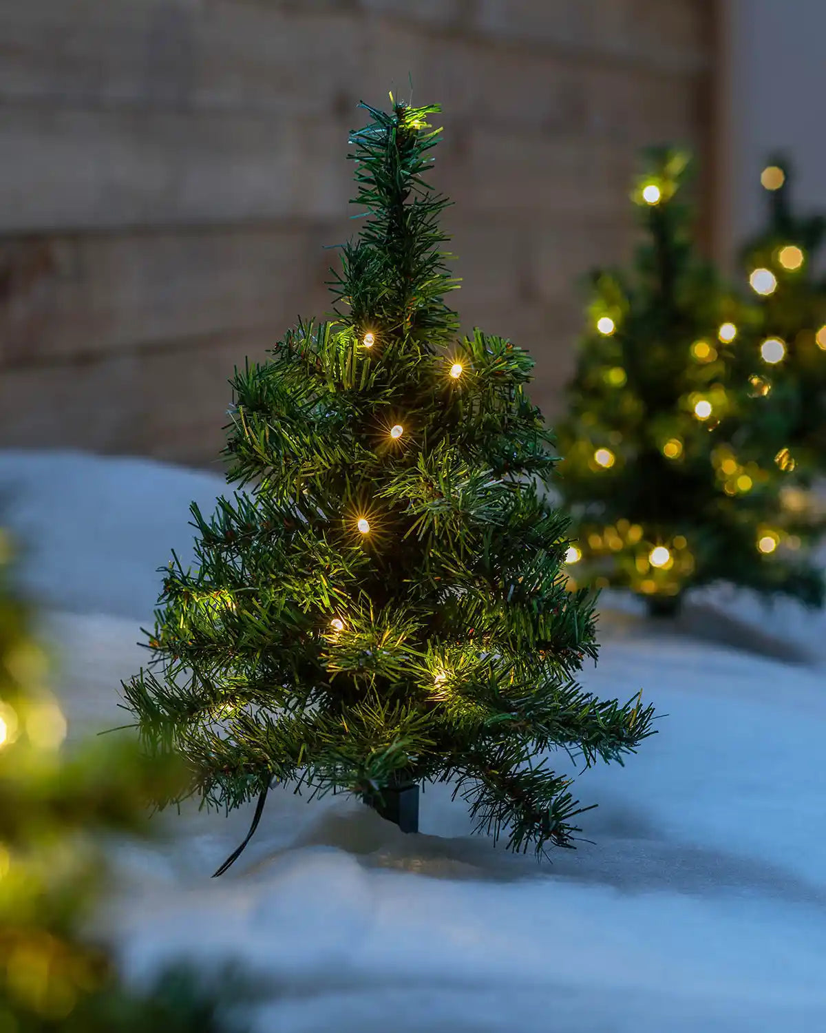 Warm white LED Christmas tree pathway stake light displayed outdoors in snow
