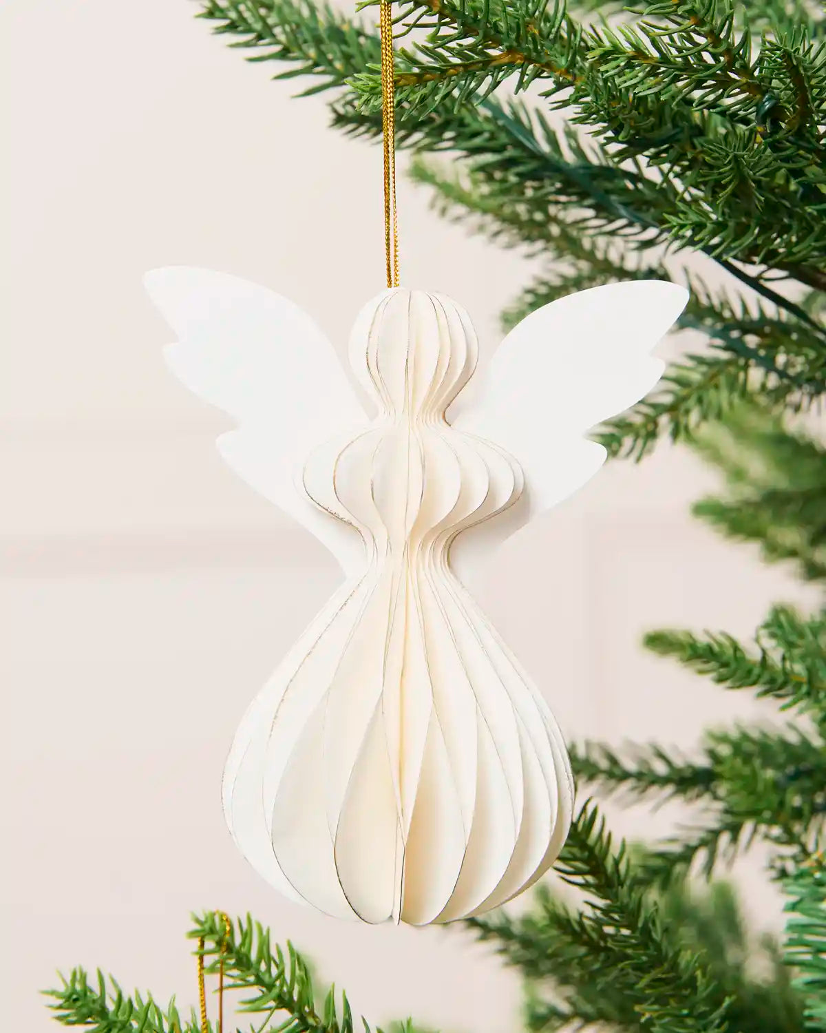 Close-up of an off-white 13 cm folded paper angel decoration on a Christmas tree.