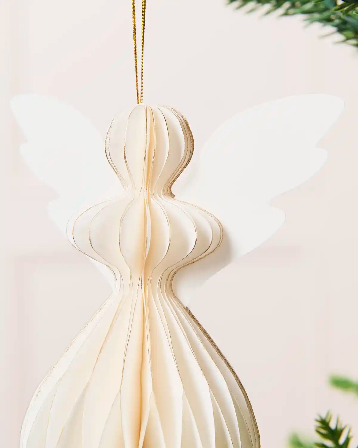 Close-up of the layered paper body, wings and gold hanging string on an angel decoration.