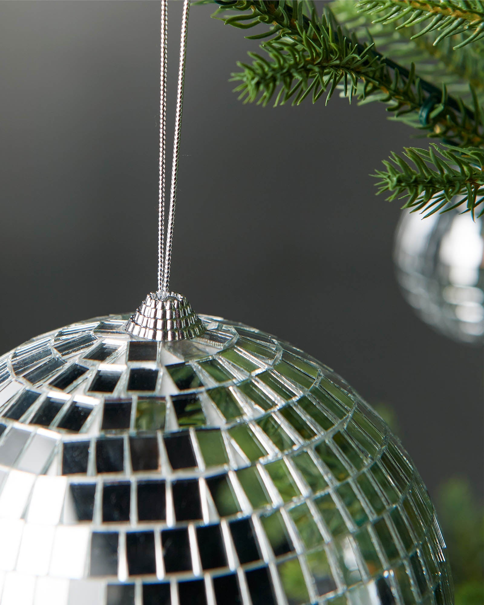 Close-up of the silver hanging string and top cap on a silver 15cm disco ball bauble.