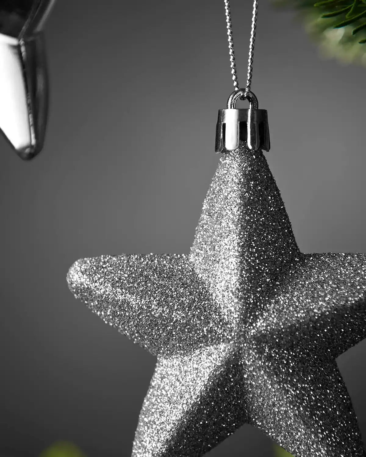 Close-up of a silver 7cm glitter hanging star with silver cap and string.