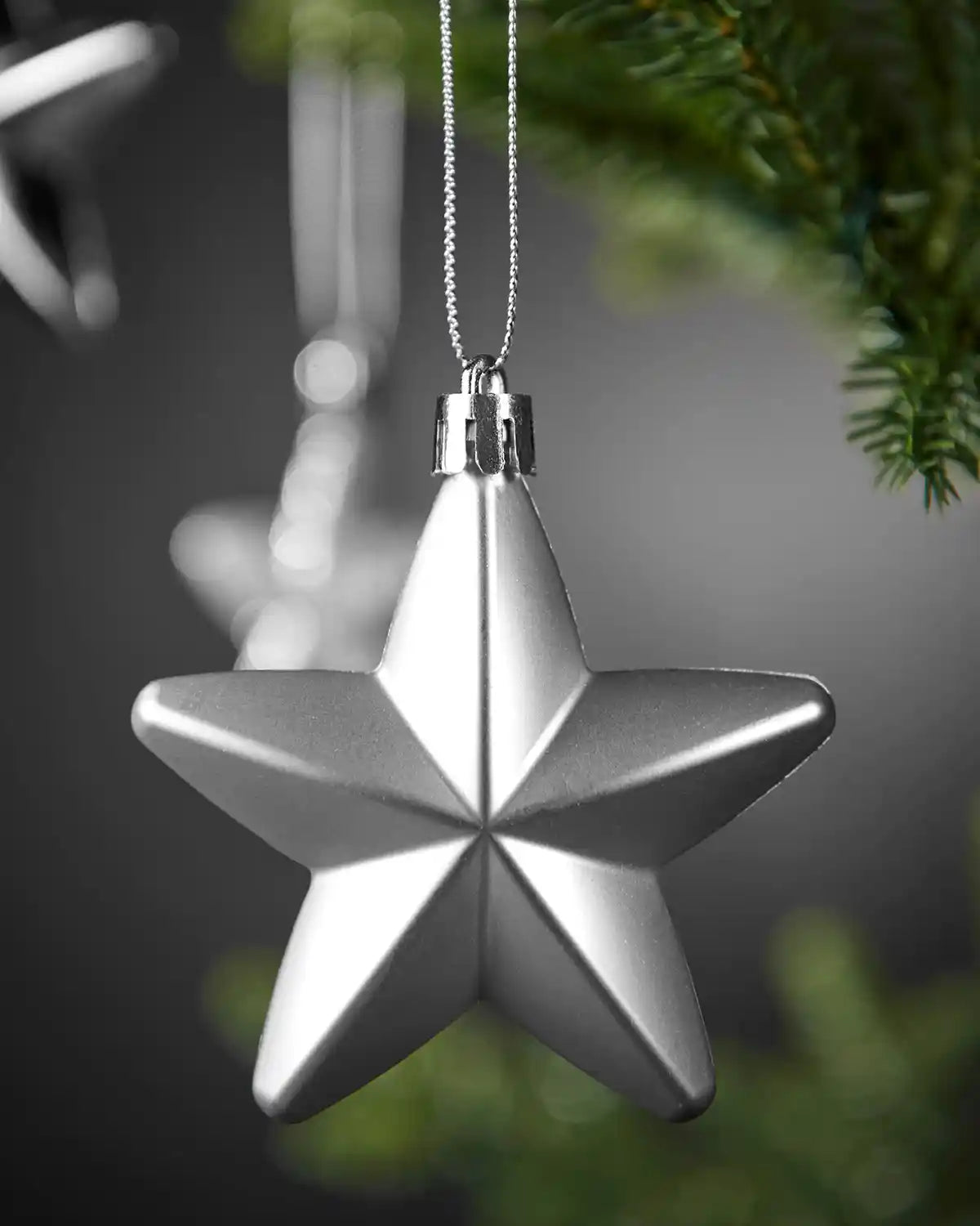 Close-up of a matte silver 7cm hanging star with silver string.