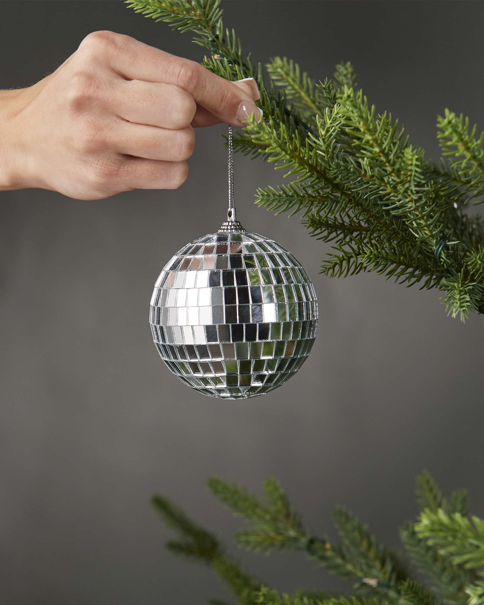 Close-up of the hanging string and top cap on a silver 8cm disco ball bauble.