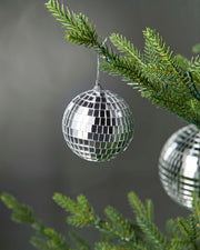 Silver 8cm disco ball bauble hanging on a Christmas tree branch.