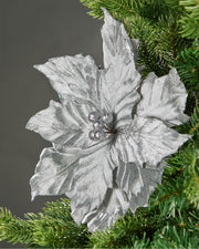 Silver artificial poinsettia flower displayed on a green Christmas tree.