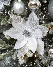 30 cm silver artificial poinsettia flower displayed on a frosted Christmas tree with silver baubles and festive decorations.