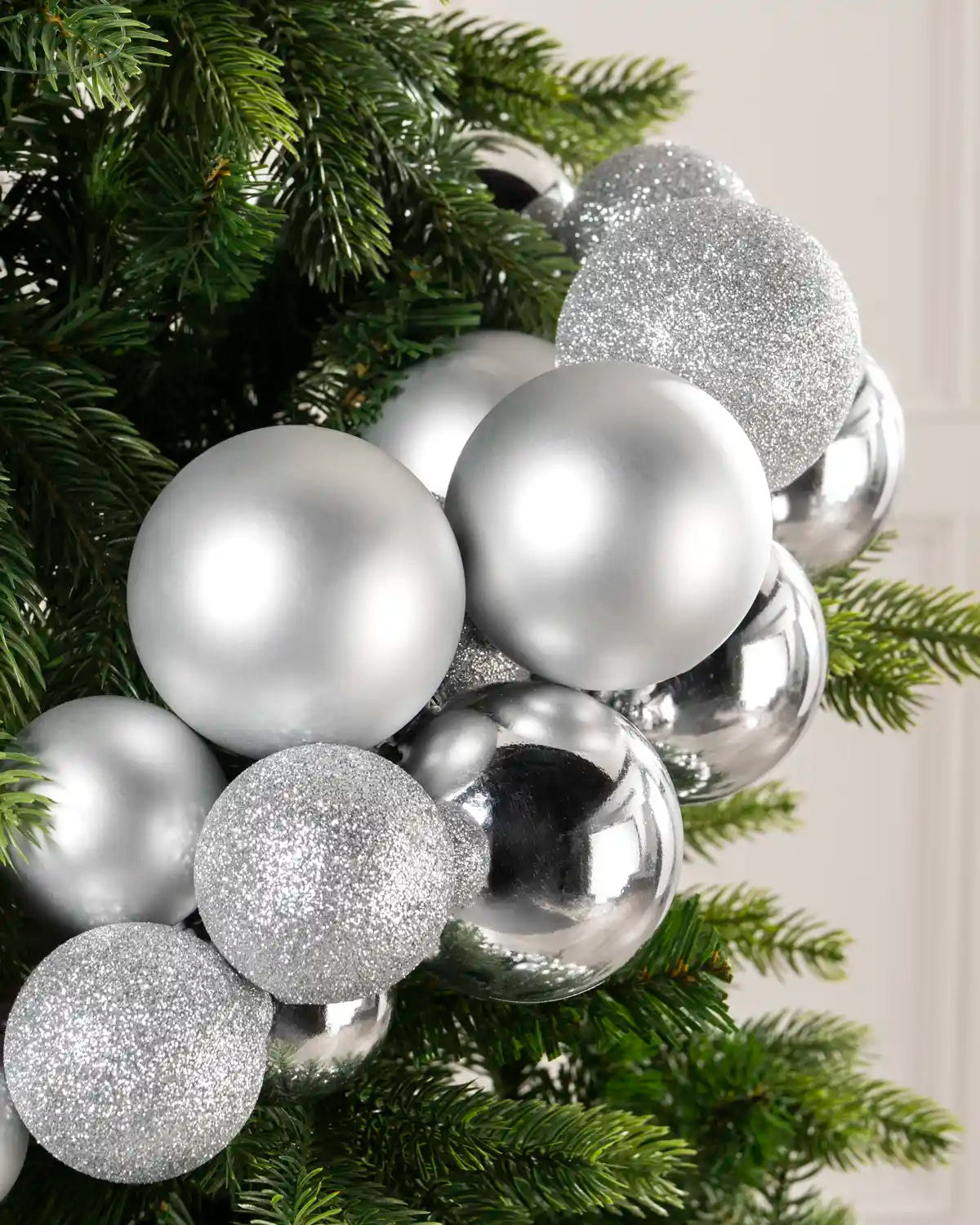 Close-up of silver baubles showing shiny, matt and glitter finishes on a Christmas tree.