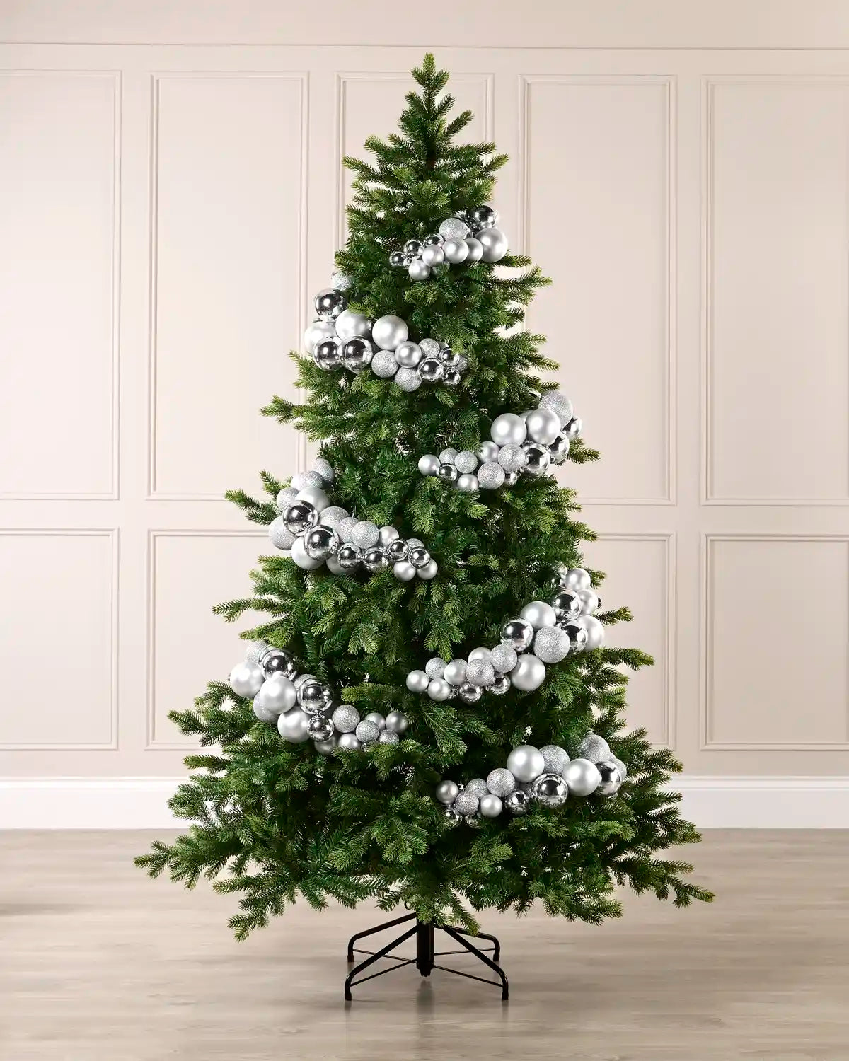 Silver bauble cluster arch styled around a green Christmas tree with shiny, matt and glitter baubles.