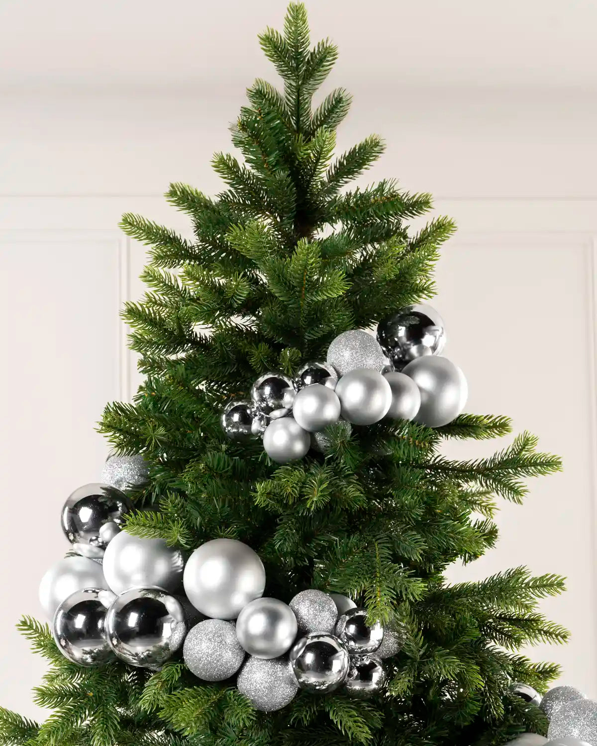 Silver bauble cluster arch arranged through the upper branches of a green Christmas tree.