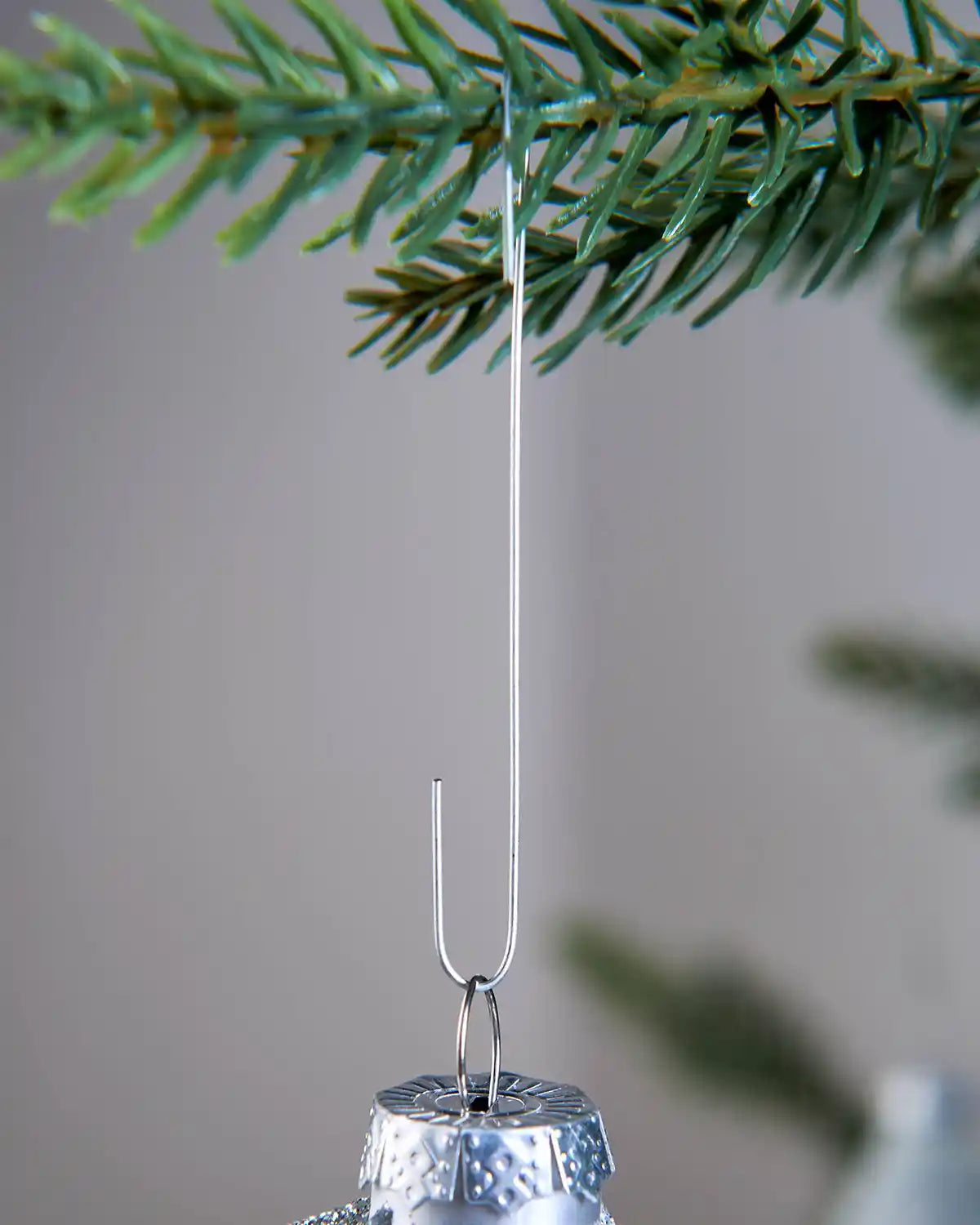 Silver bauble ornament hook attached to a Christmas tree branch