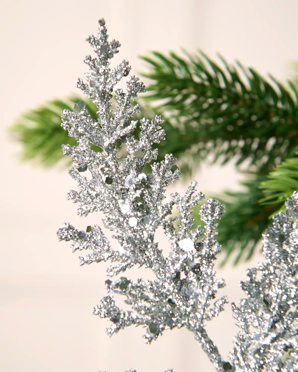 Close-up of silver glitter leaf foliage with scattered reflective sequins and a textured sparkling finish.