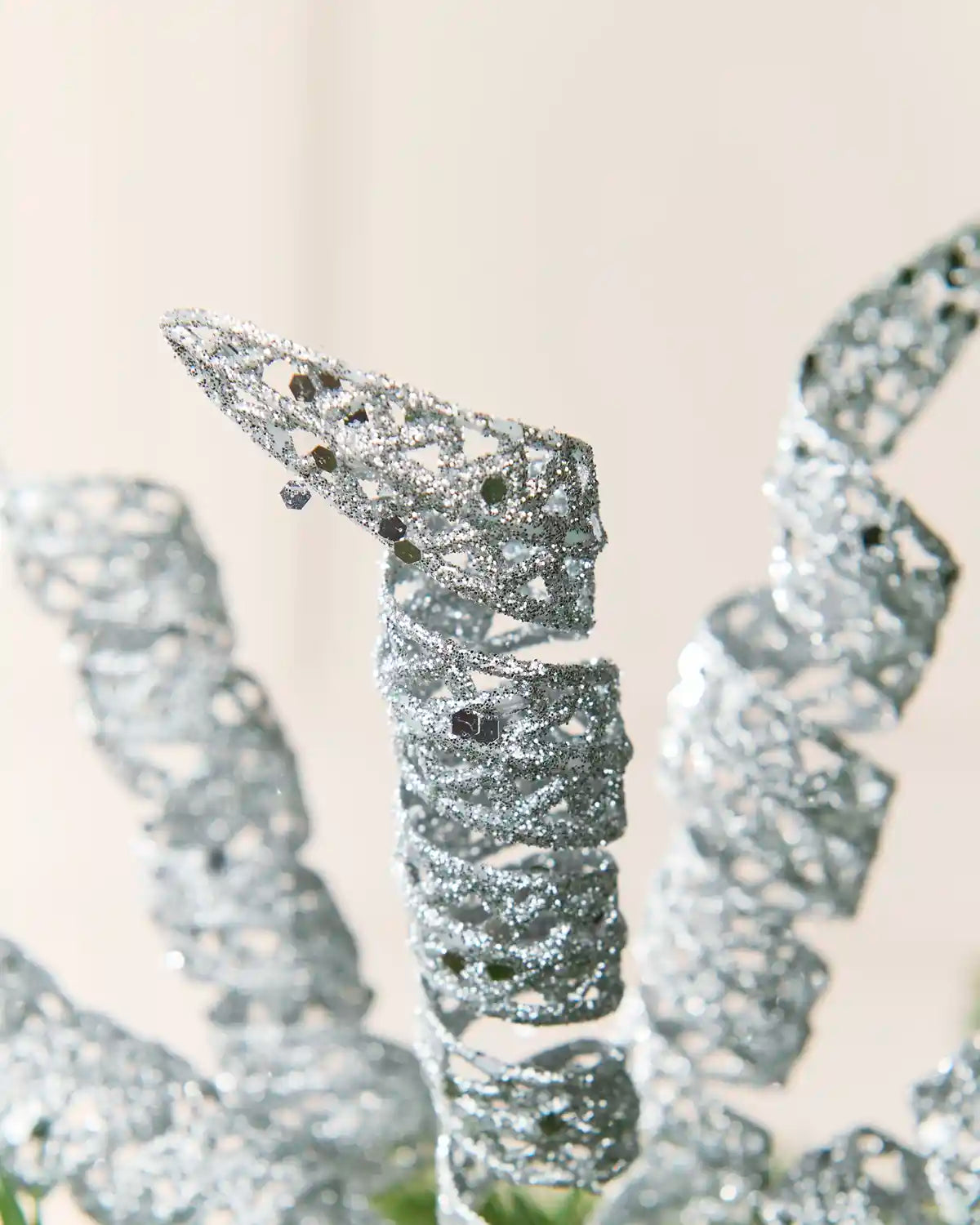 Detailed view of a silver glitter spiral pick showing its curled shape and textured reflective finish.