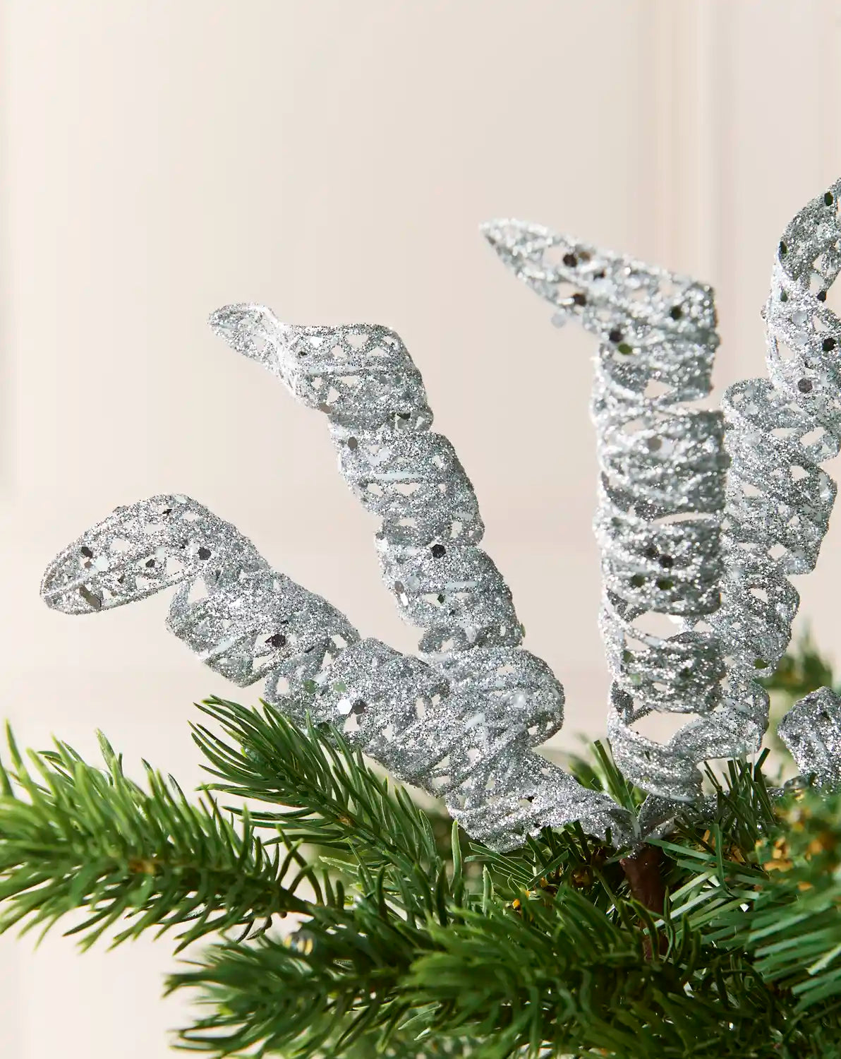 Close-up of silver glitter spiral picks showing curled openwork shapes and reflective sequin details.