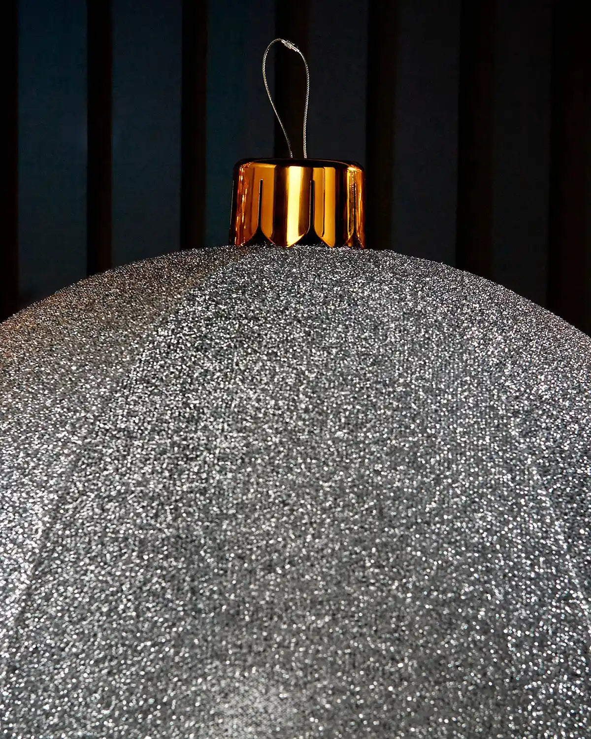 Close-up of the gold cap and hanging wire on a silver inflatable tinsel Christmas bauble.