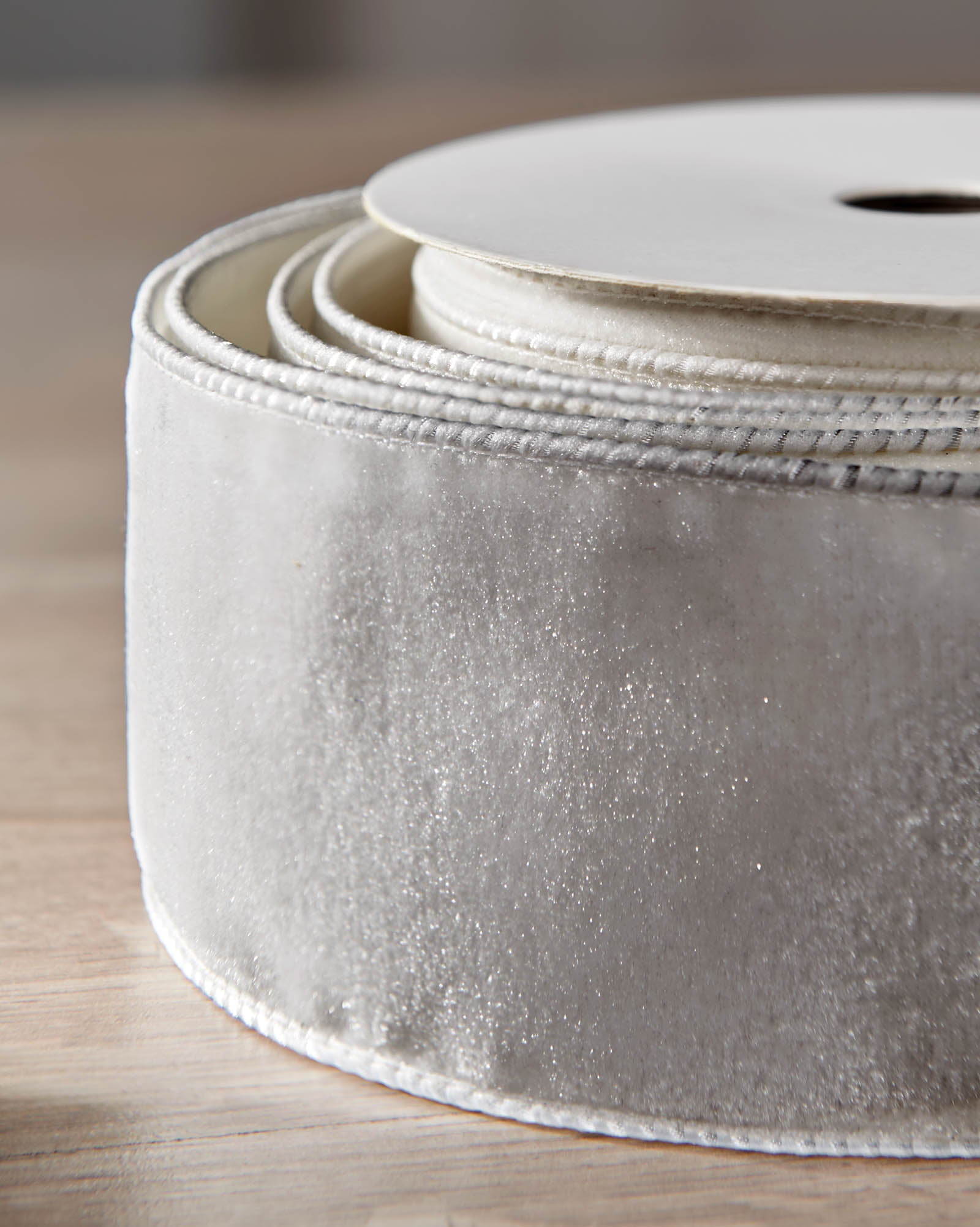 Close-up of silver velvet ribbon on a roll, showing the soft texture and wired edge.
