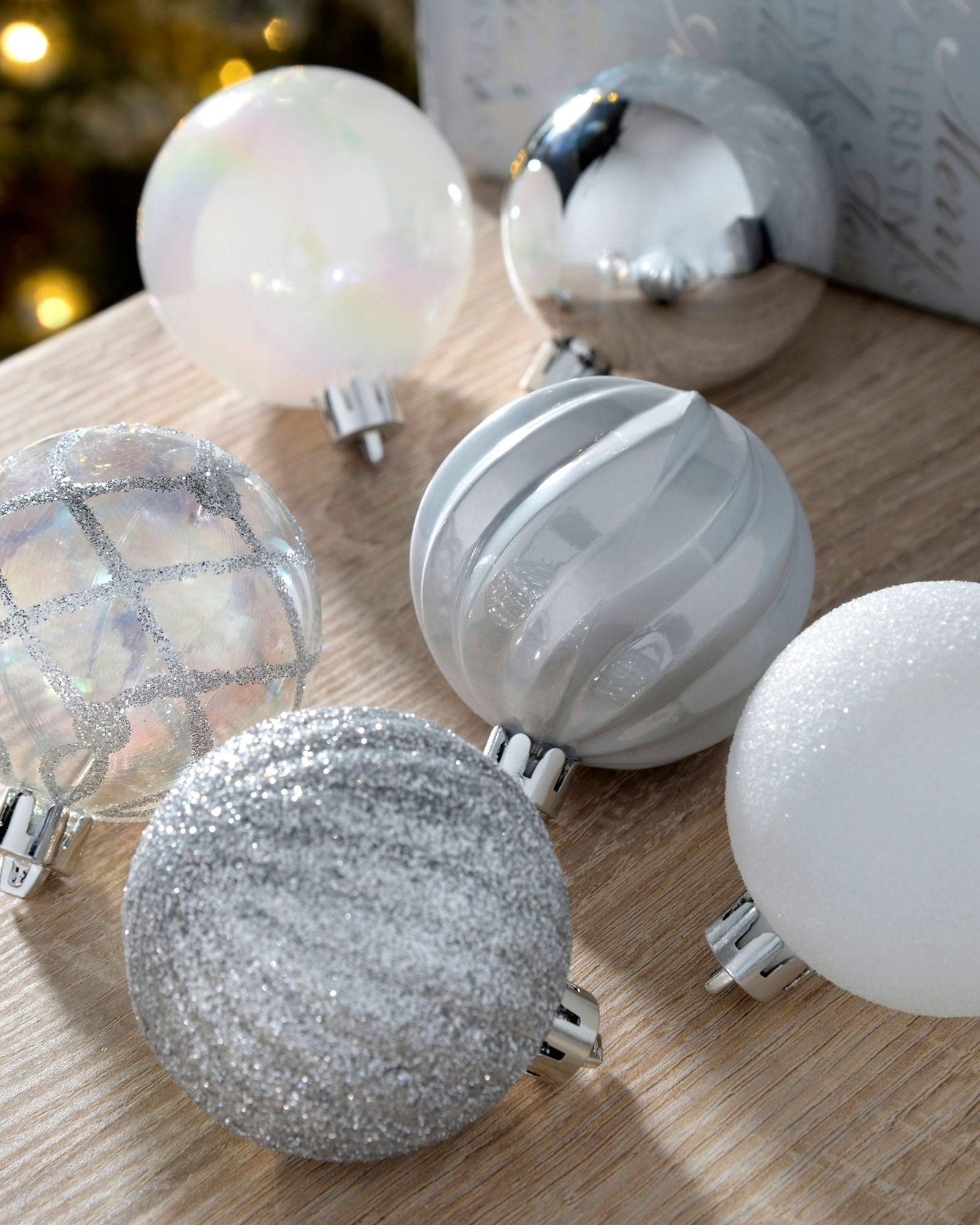 Close-up of silver and white 6cm baubles with glitter, pearl, mirrored and ribbed finishes