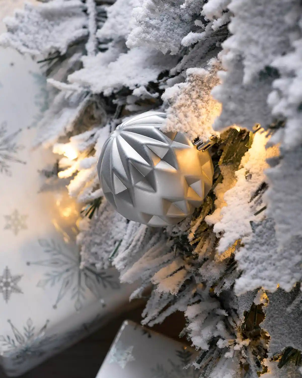 Close-up of a silver bauble on the snow flocked Christmas tree