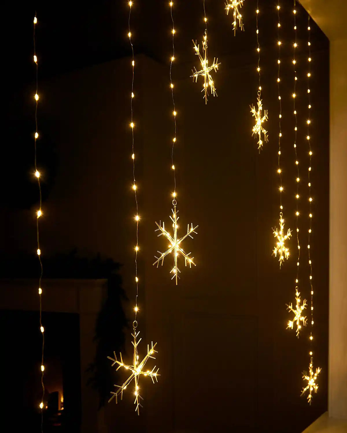 Close-up of illuminated warm white snowflake curtain string lights hanging indoors