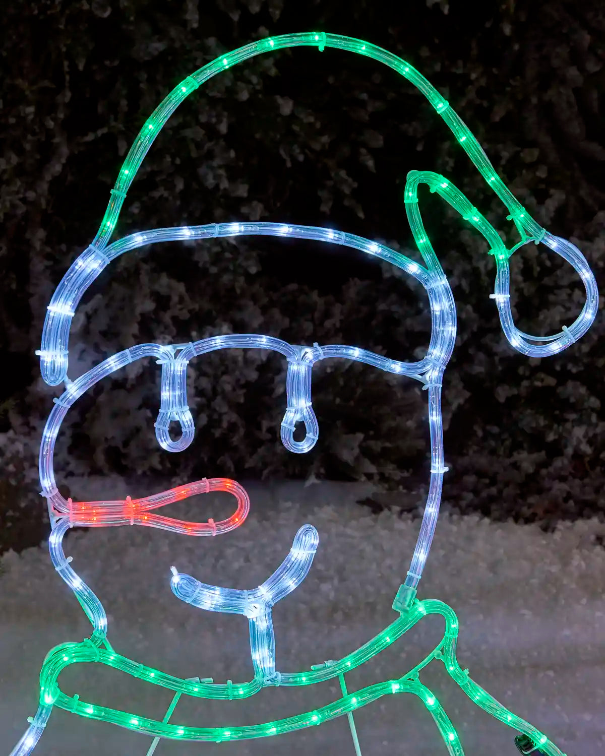 Close-up of a pre-lit carolling snowman rope light silhouette with a green Santa hat, white face, and glowing green scarf