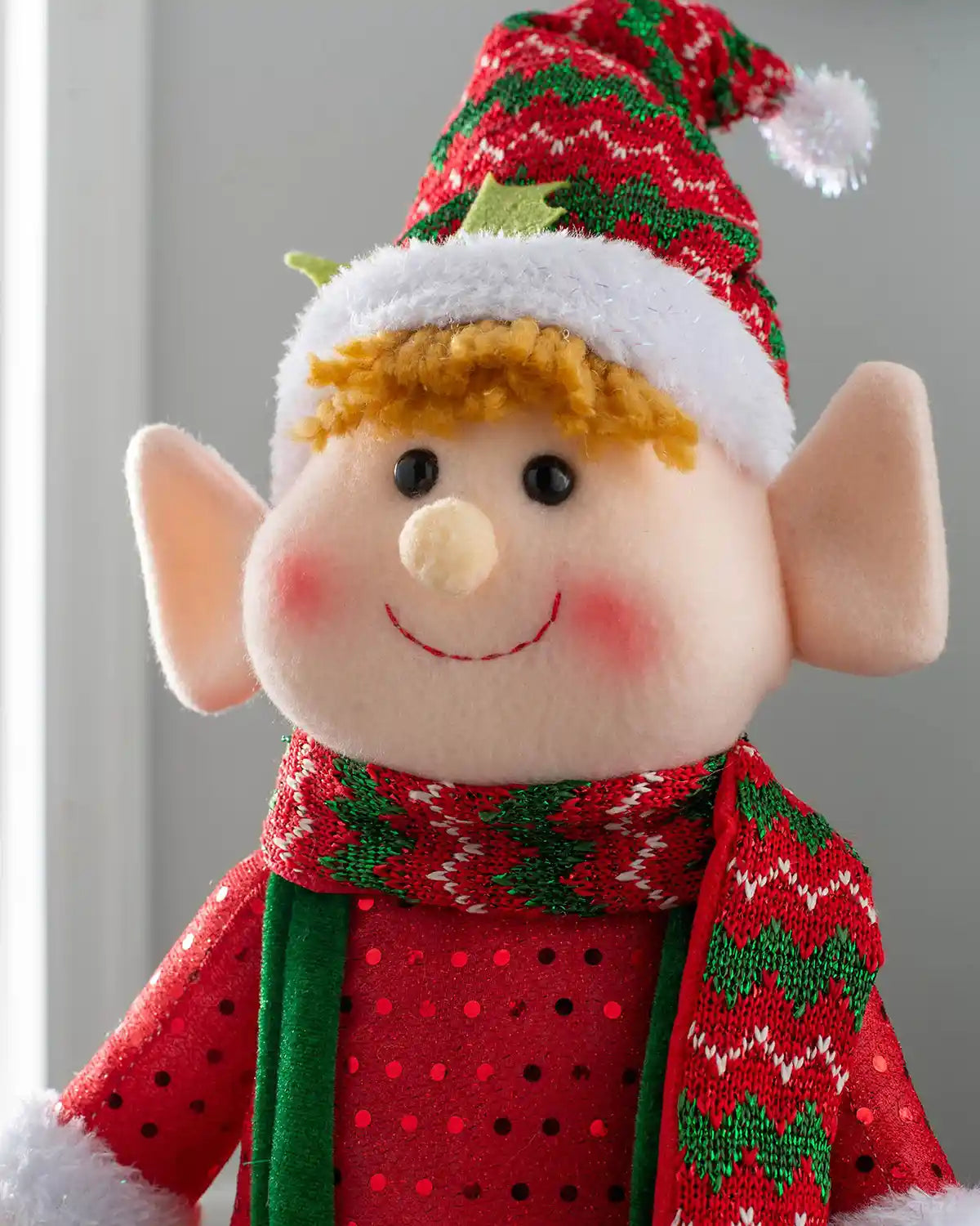 Close-up of the standing elf boy figurine with a red and green scarf and festive hat
