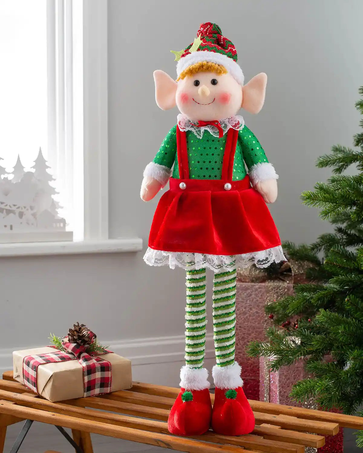 Standing elf girl figurine, 60 cm, displayed on a bench beside Christmas presents and a tree