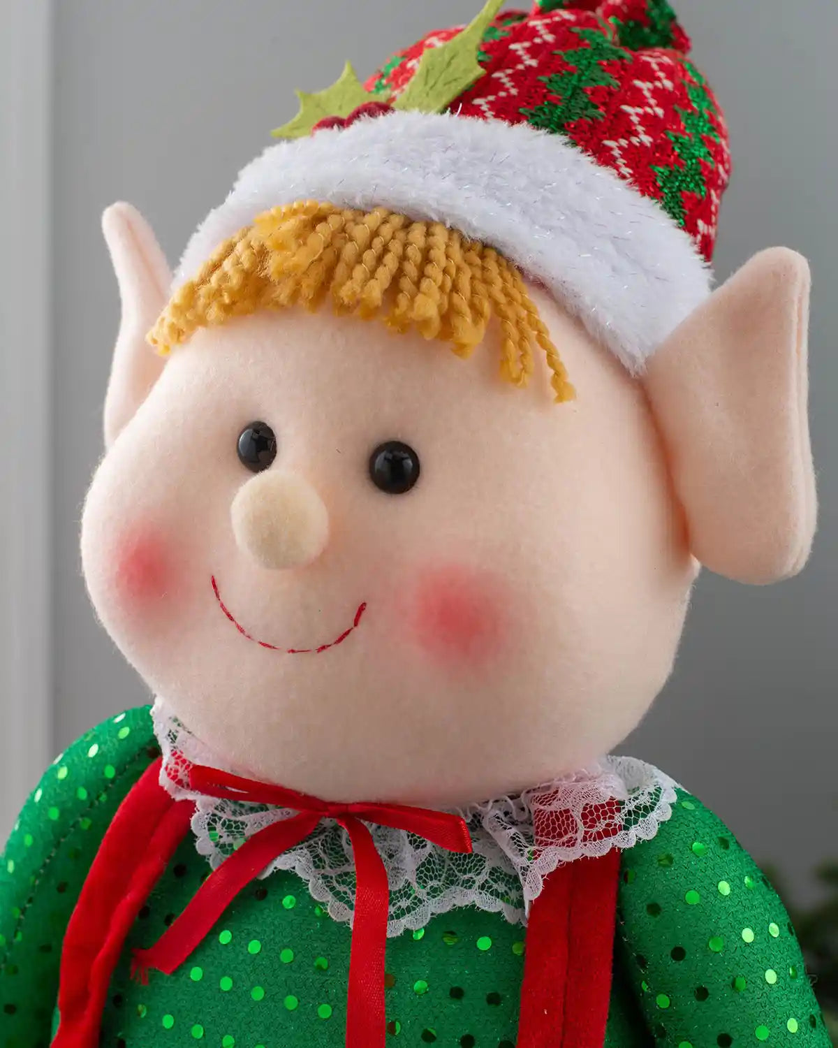 Close-up of the standing elf girl figurine with a red and green holly-trimmed hat