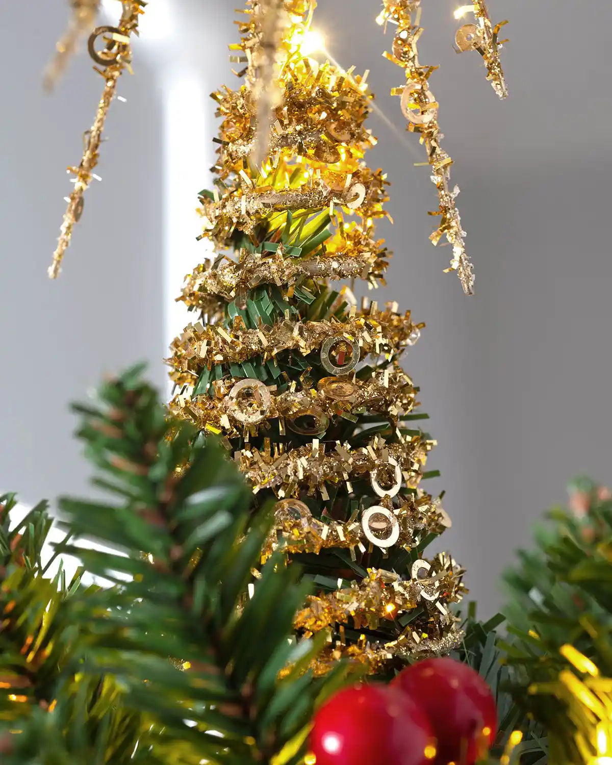 Close-up of gold tinsel starburst tree topper with glitter detail and warm white lights