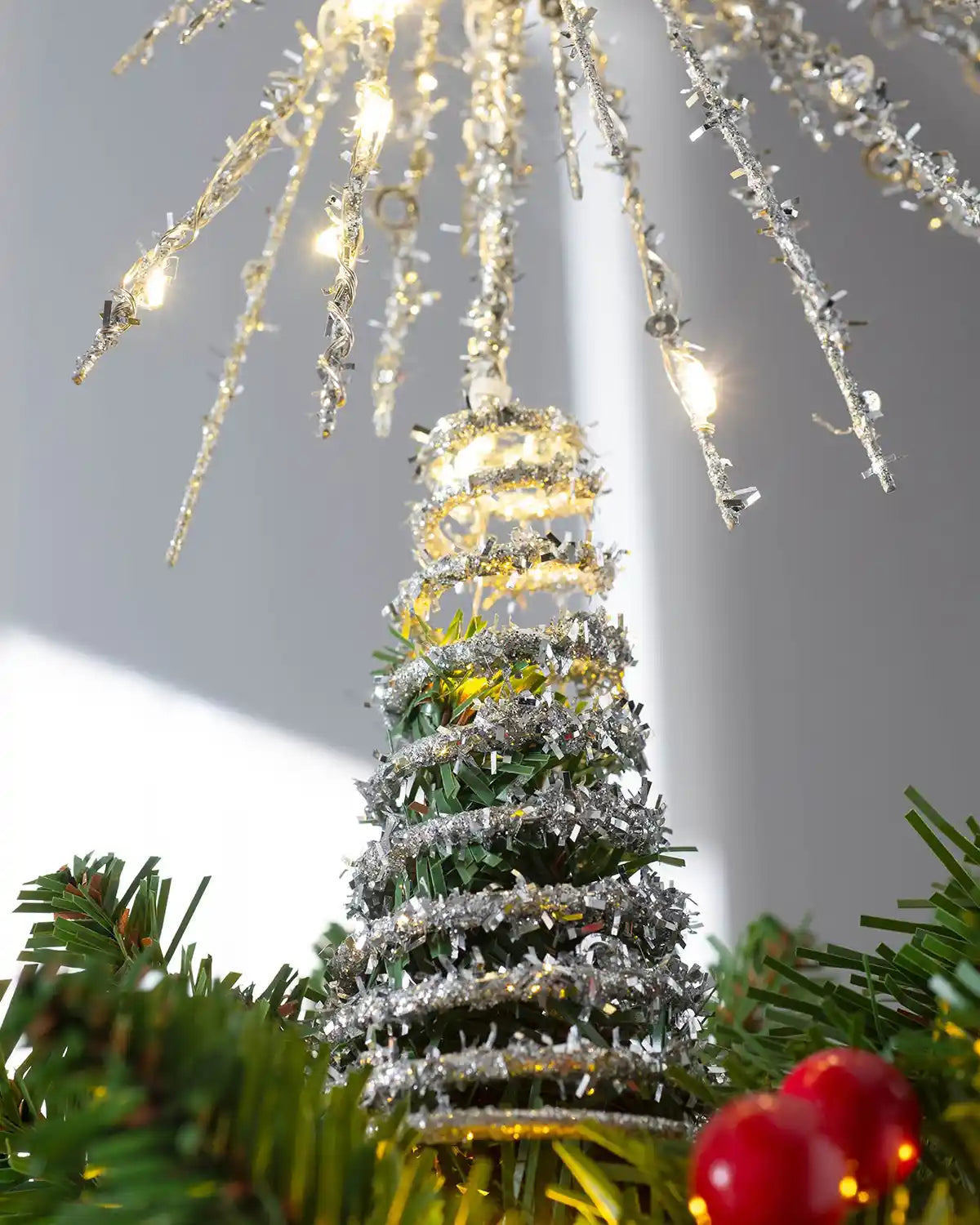 Close-up of silver tinsel starburst tree topper with glitter detail and warm white lights