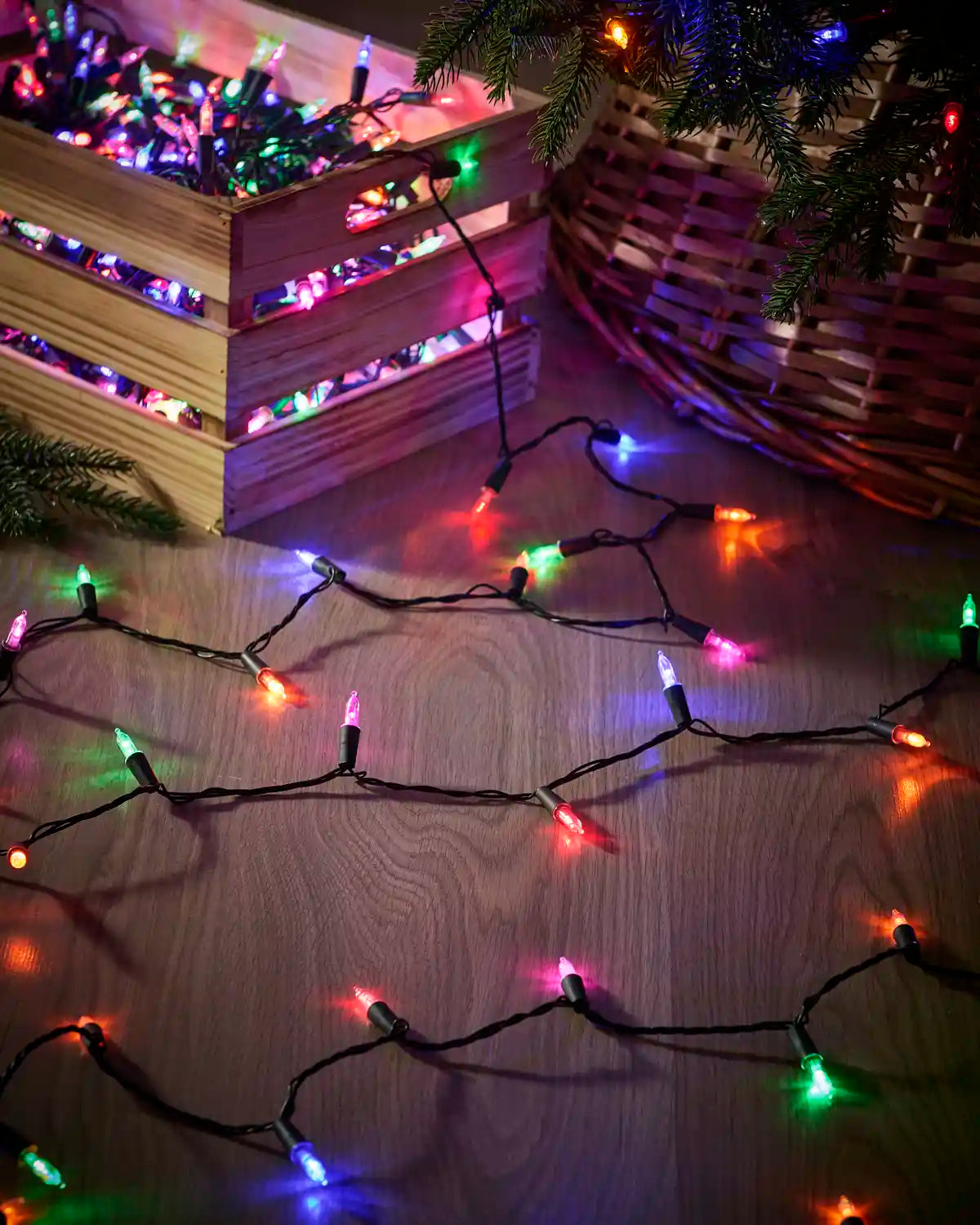 Multi-colour vintage candle string lights with black cable arranged beside a Christmas tree.