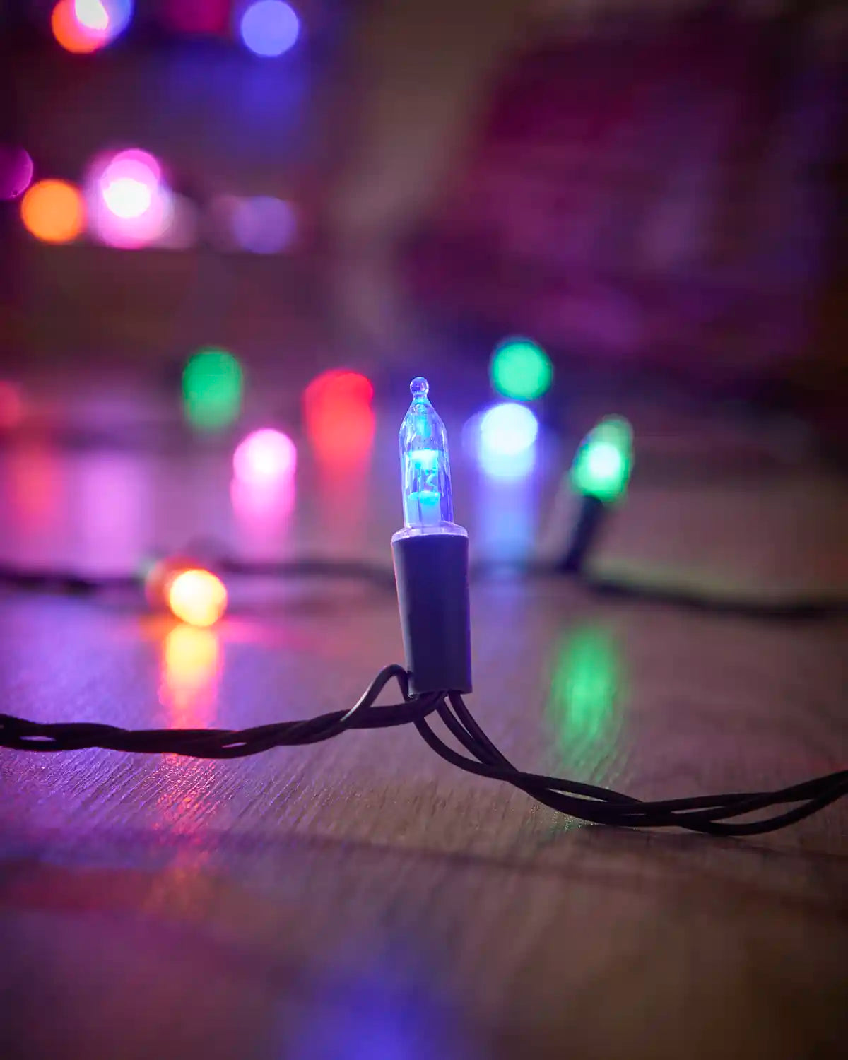 Close-up of a blue vintage candle LED bulb with multi-colour lights in the background.
