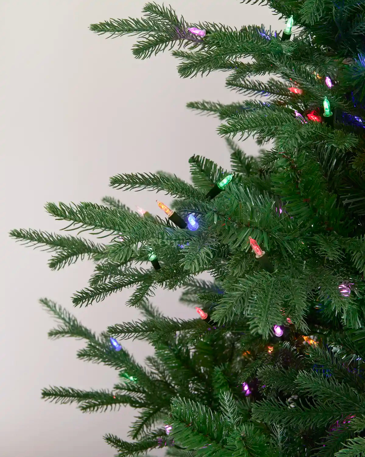 Multi-colour vintage candle string lights displayed throughout a green Christmas tree.