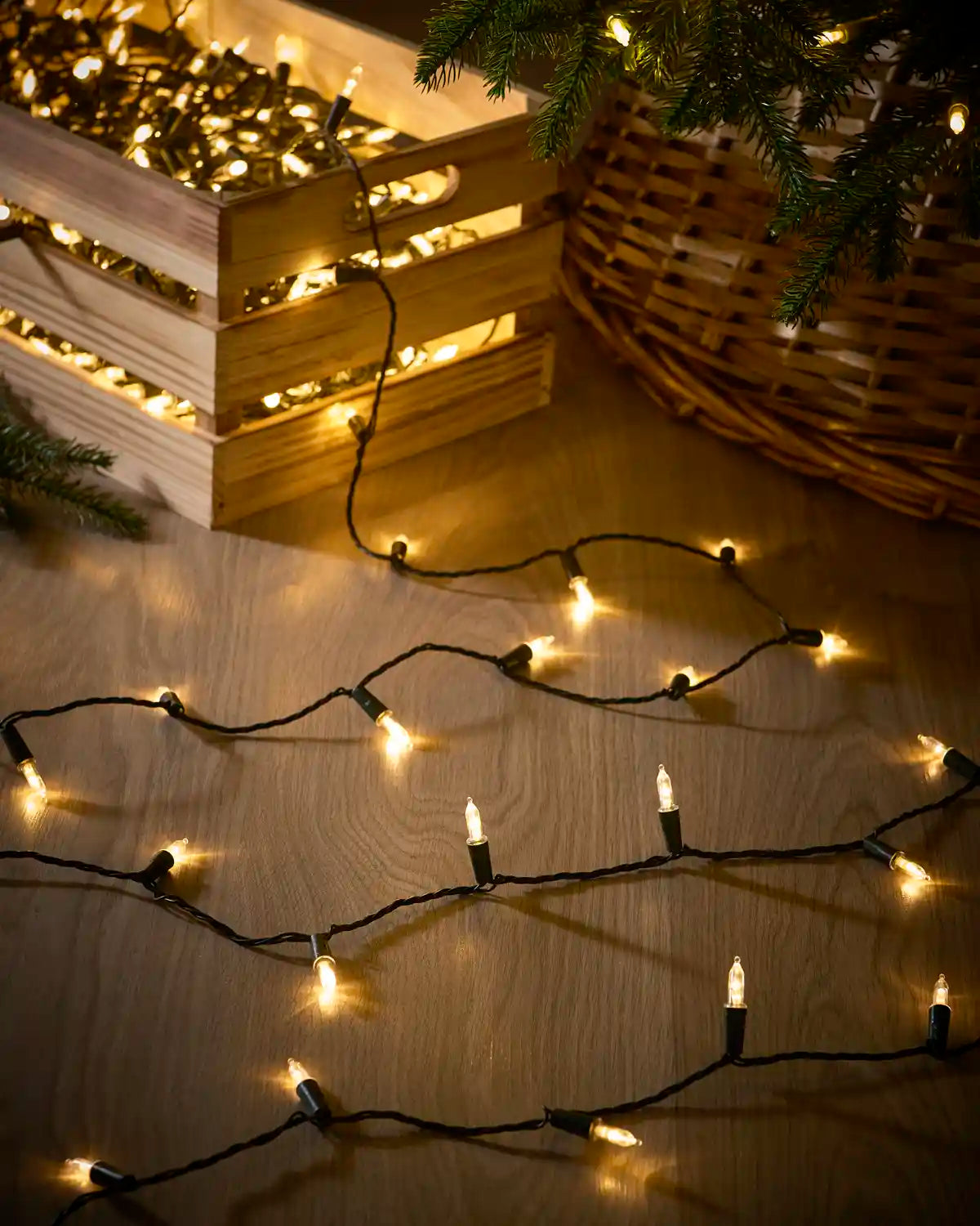 Warm white vintage candle string lights with black cable arranged beside a Christmas tree.