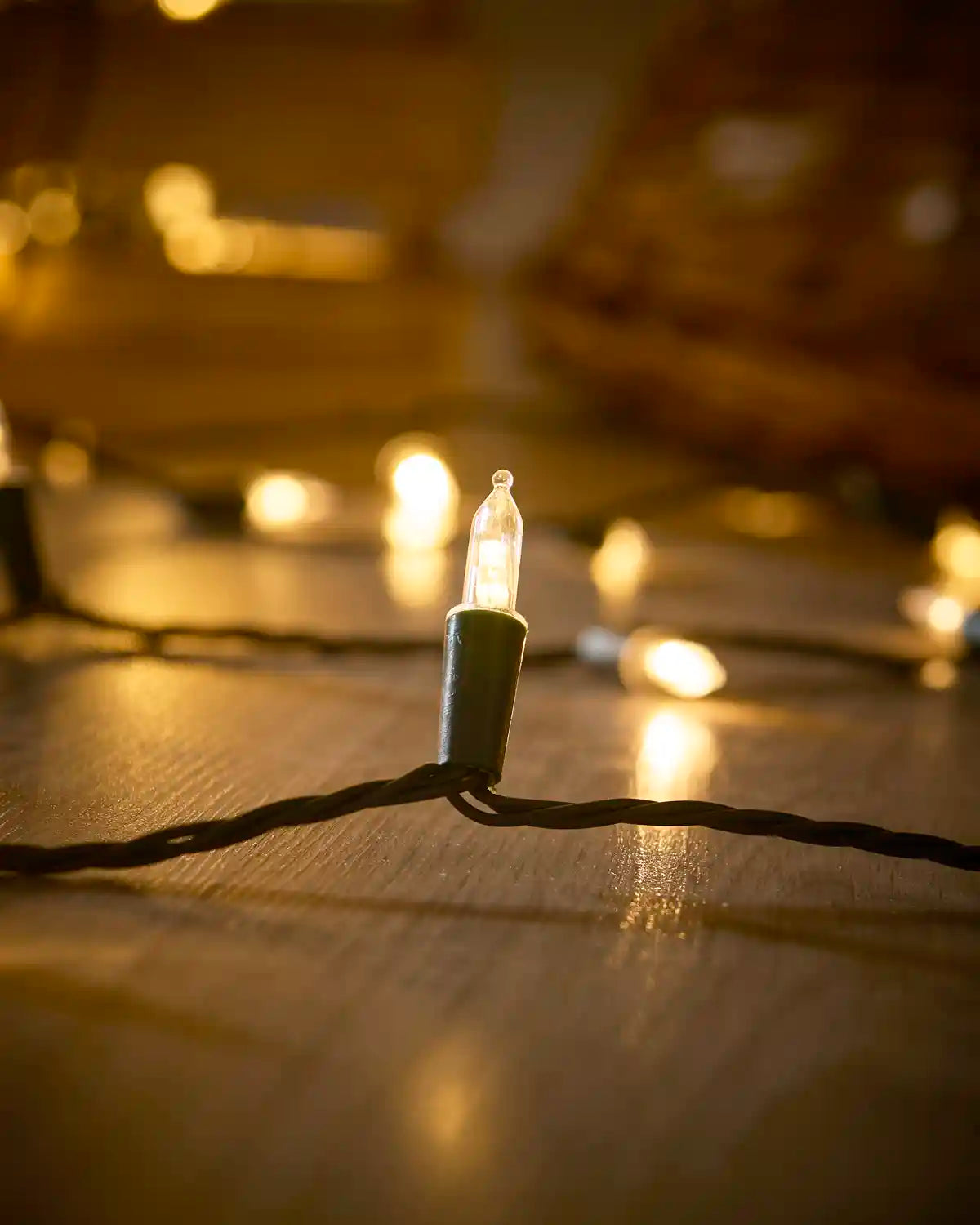 Close-up of a warm white vintage candle LED bulb on black string light cable.