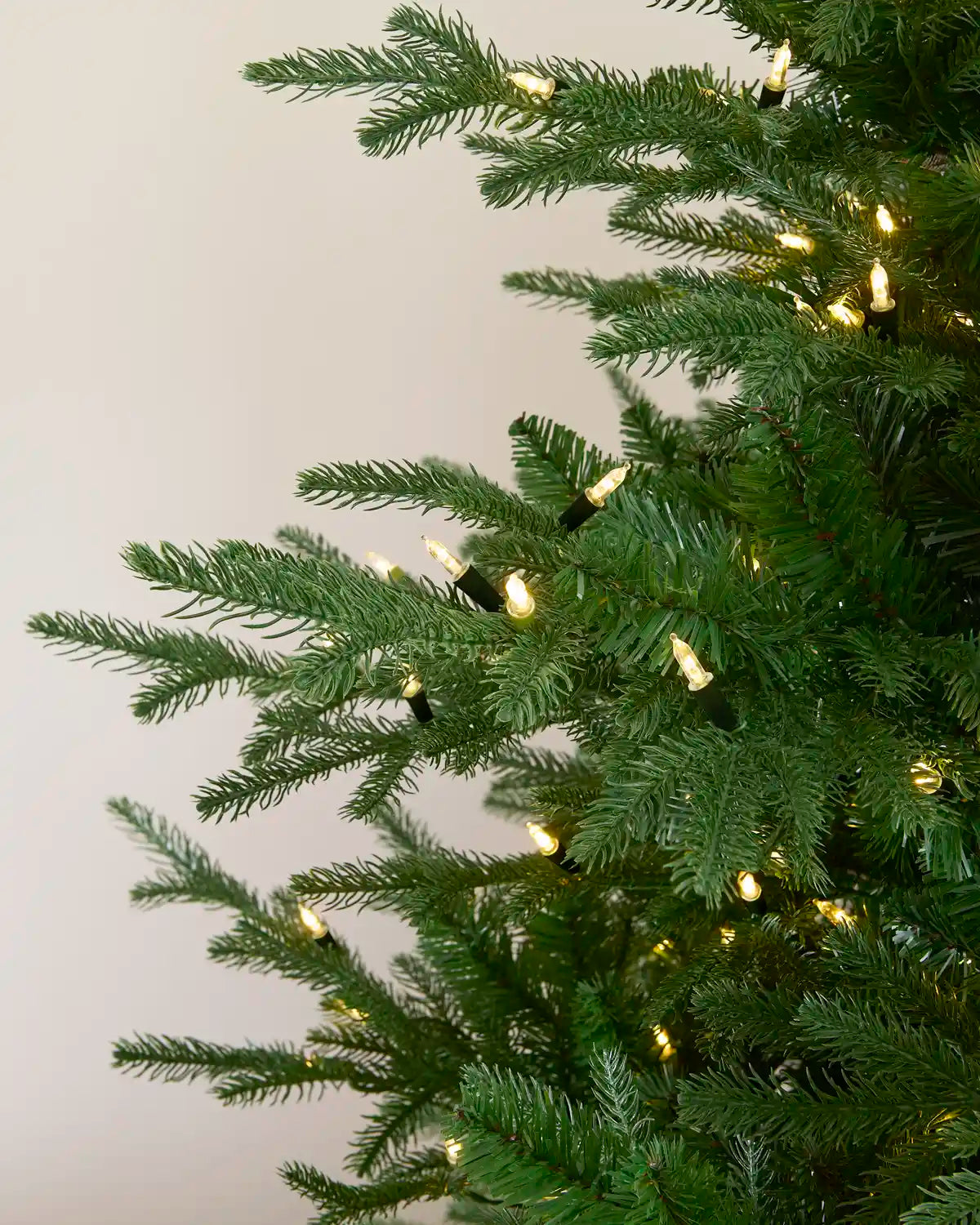 Warm white vintage candle string lights displayed throughout a green Christmas tree.