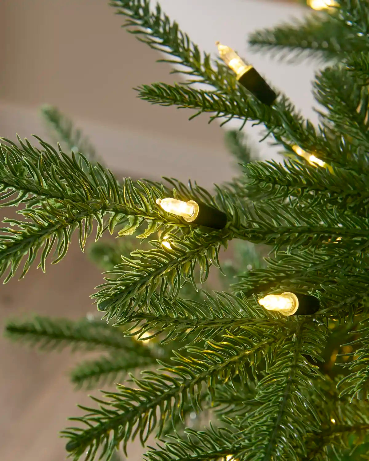 Close-up of warm white candle-style LED bulbs illuminated among Christmas tree branches.