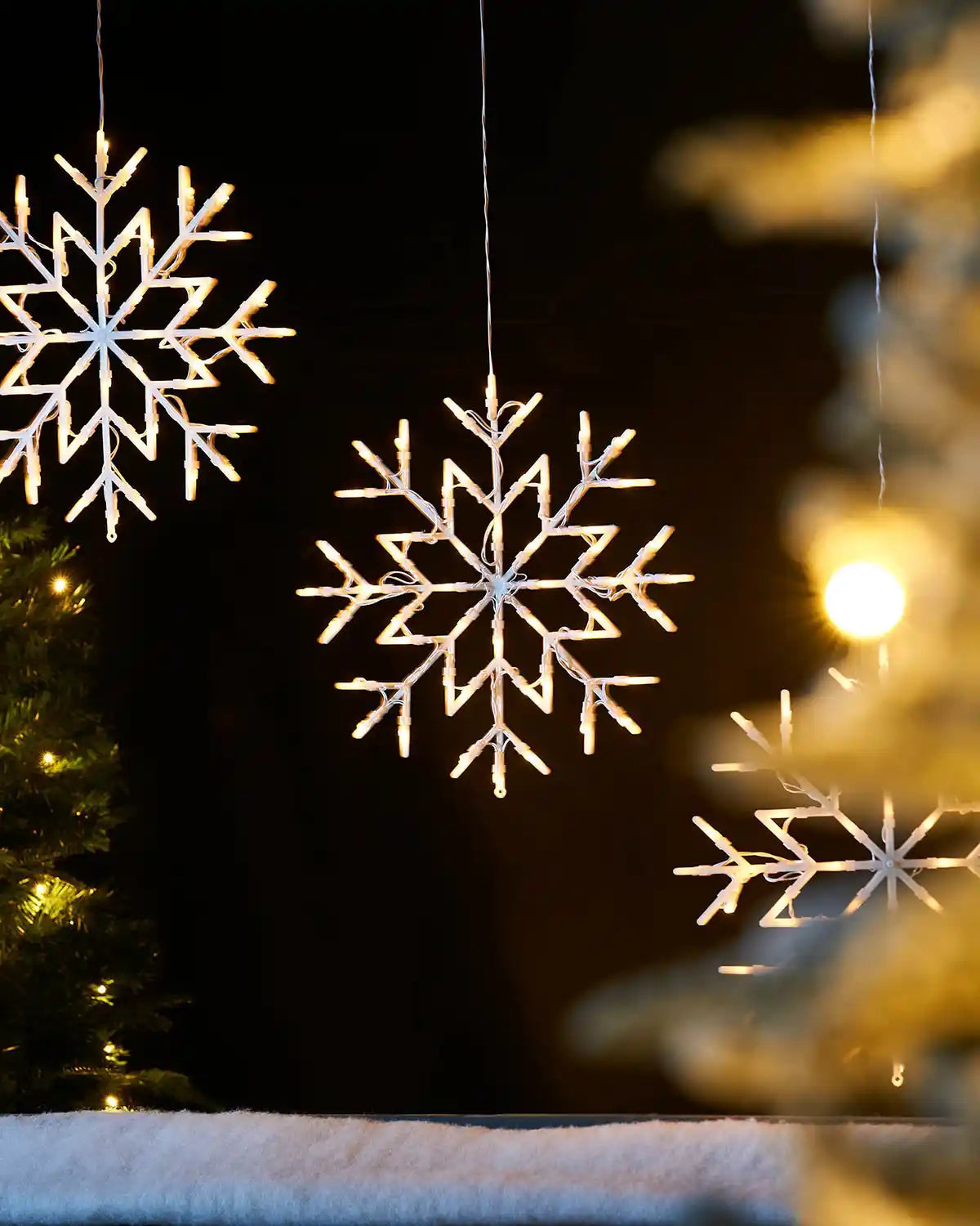 36 cm warm white LED snowflake silhouette hanging in a festive window display