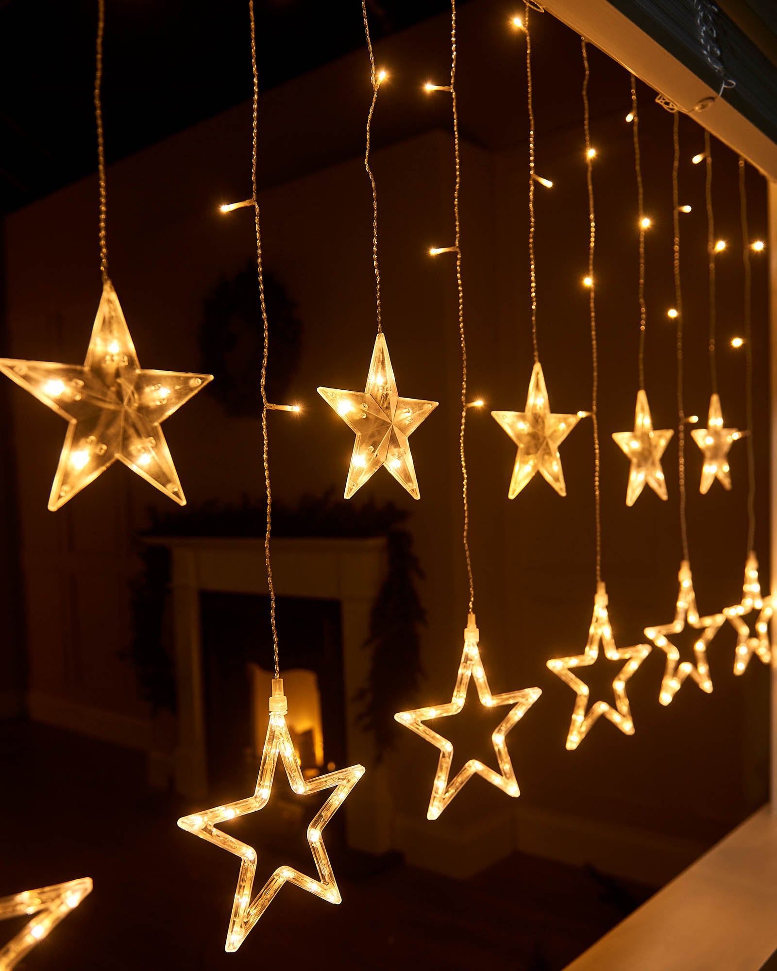 Close-up of warm white star curtain lights with hanging strands and clear illuminated star shapes