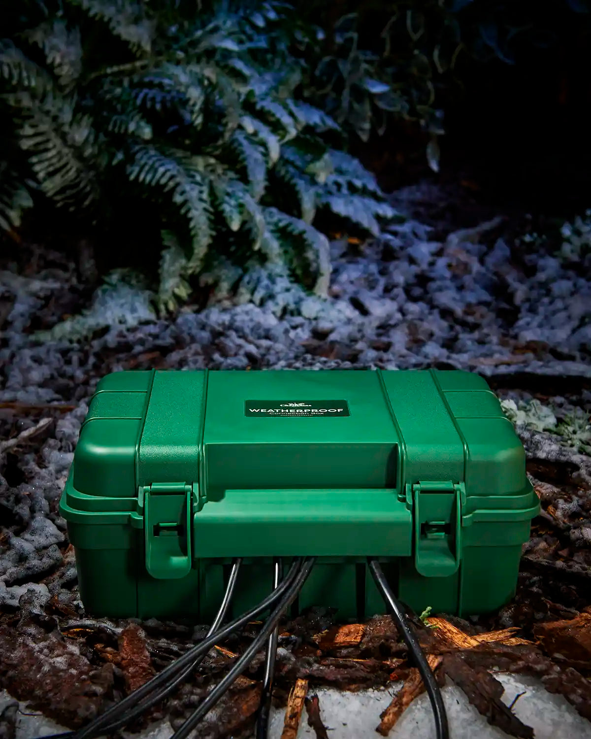 Closed green weatherproof electrical box with cables running from the base.