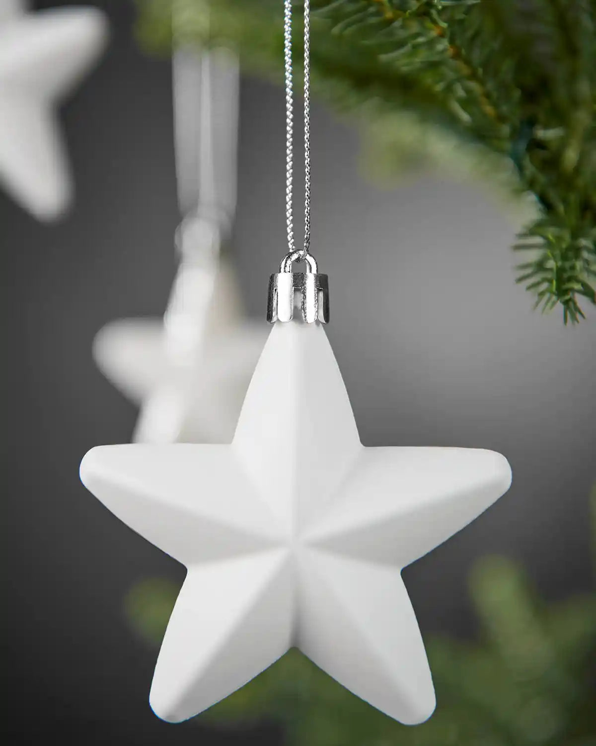 Close-up of a smooth white 7cm hanging star on a silver string.