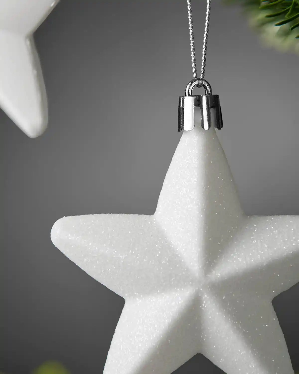 Close-up of a white 7cm glitter star with silver hanging string.