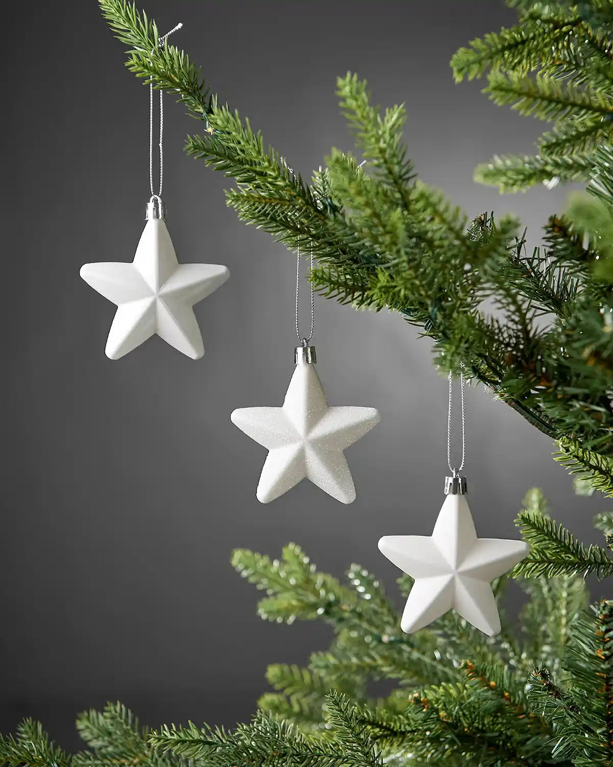 White 7cm hanging star decorations displayed on a Christmas tree.