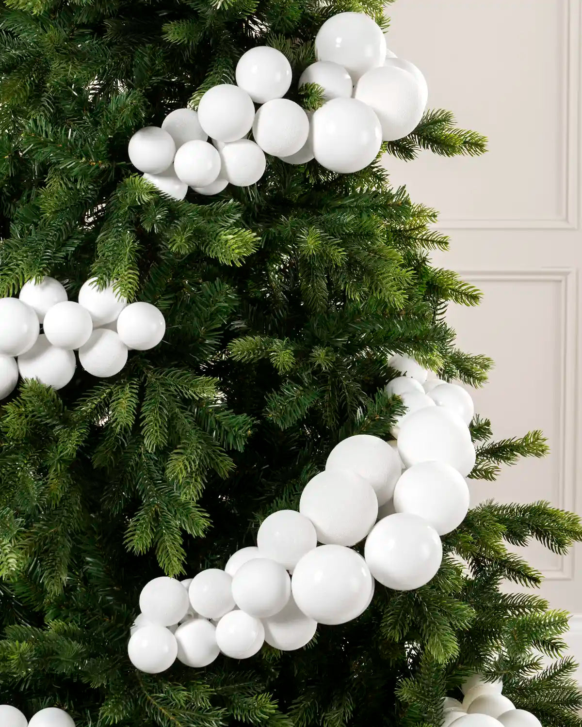 Close-up of white bauble cluster arch on a Christmas tree showing mixed sizes and finishes.