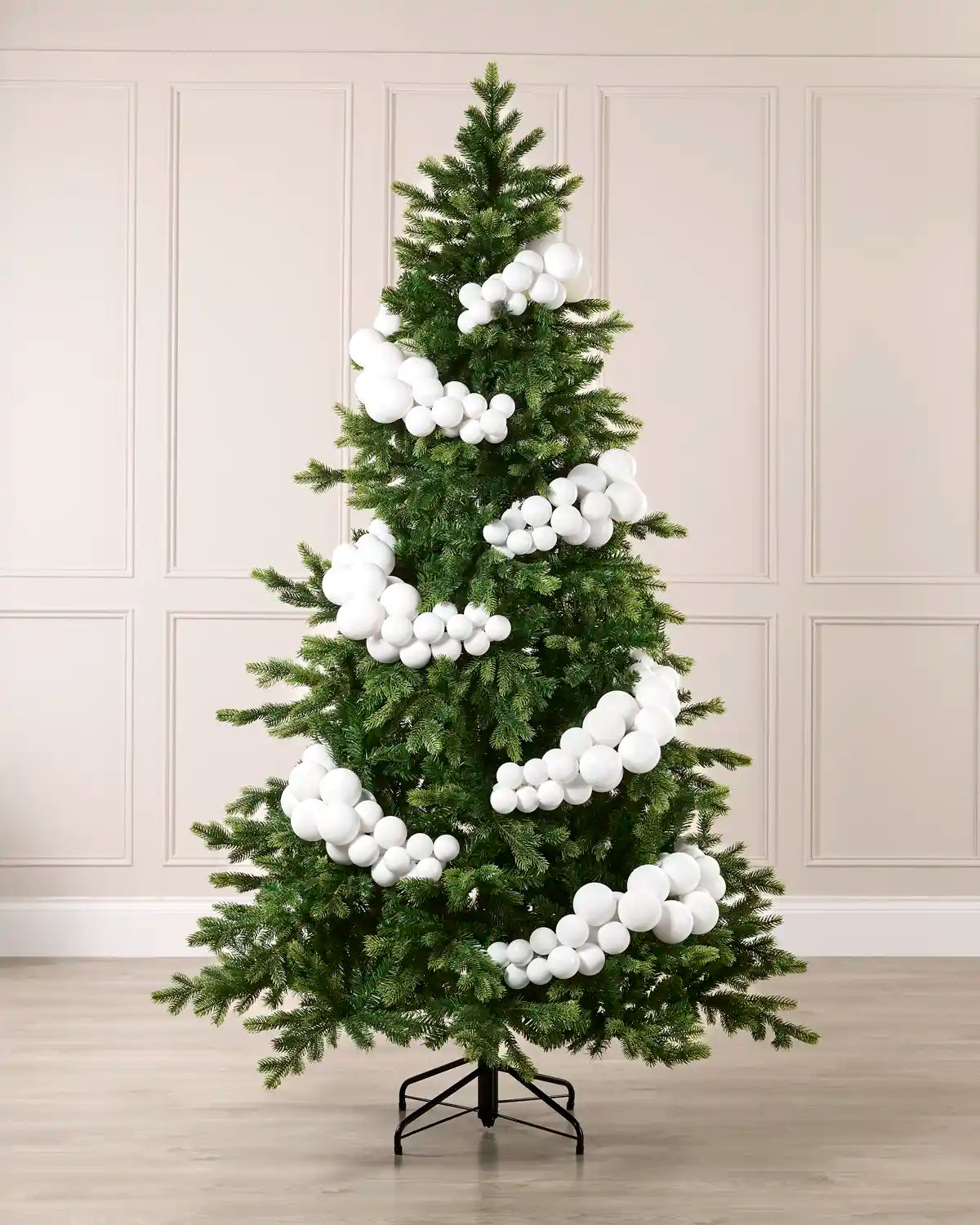 White bauble cluster arch styled around a green Christmas tree with shiny, matt and glitter baubles.