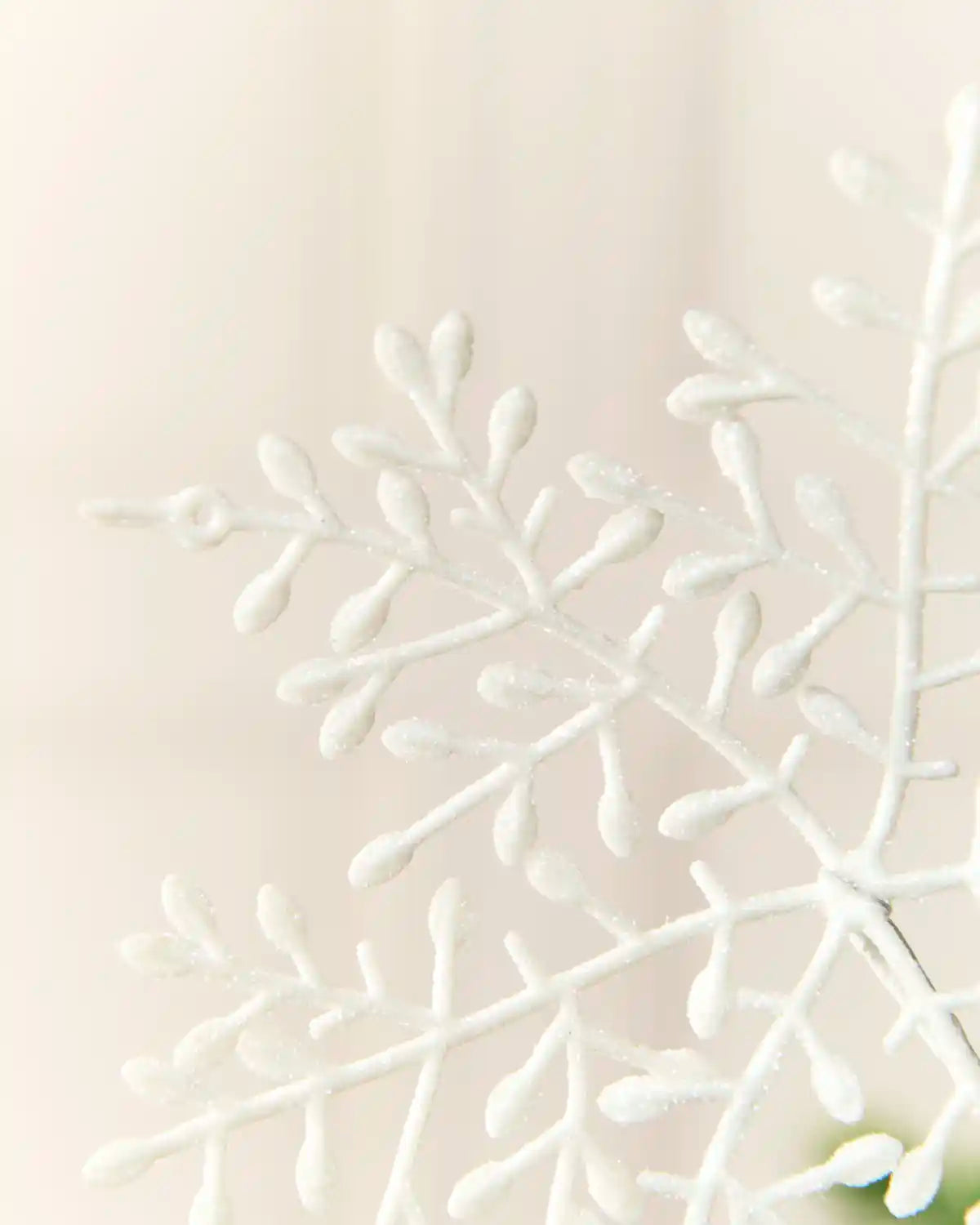 Close-up of the delicate white glitter branches and rounded tips on a snowflake spray.