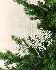 White glitter snowflake sprays arranged among the branches of a green Christmas tree.