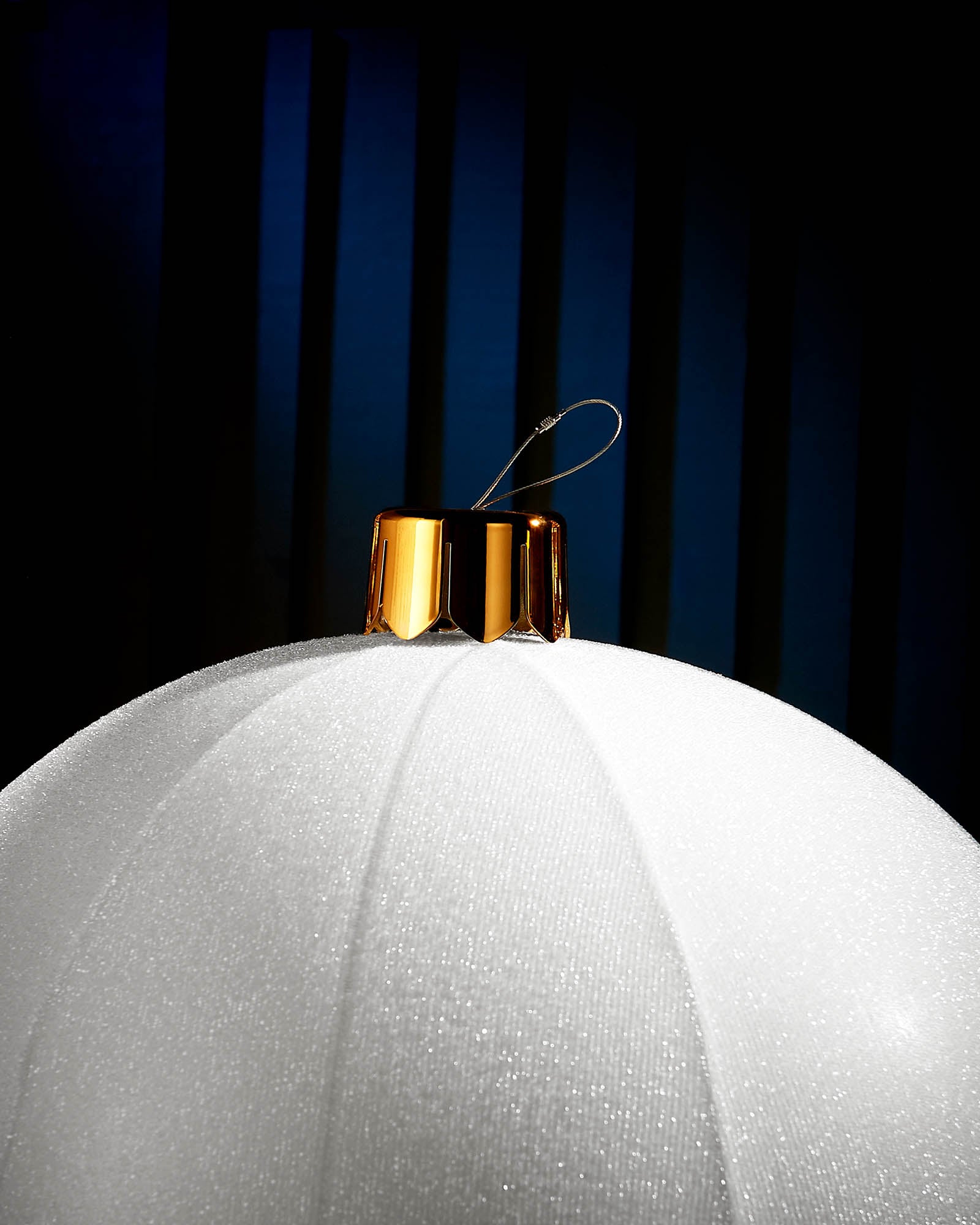Close-up of the gold cap and hanging wire on a white inflatable tinsel Christmas bauble.